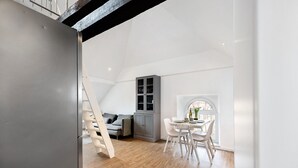 Un loft modern amb zona de menjador, un armari gris i una escala.