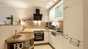 Una cocina compacta con horno integrado, microondas y encimera de madera.