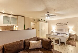 Une chambre à coucher avec un lit, une table de chevet et un ventilateur de plafond.