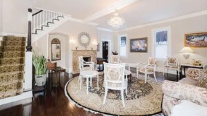 Un salón amplio con chimenea, muebles blancos y una lámpara de araña grande.