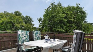 Un patio con un tavolo apparecchiato per mangiare, circondato da sedie con cuscini decorati.