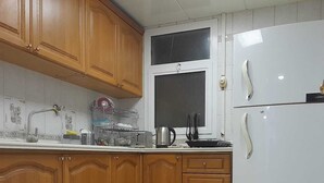 Eine Küche mit Holzausstattung, einem weißen Kühlschrank und einem Fenster über der Spüle.