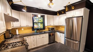 A modern kitchen with stainless steel appliances, white cabinets, and a window with a view. - Renovated Coastal Retreat • Walk to Town • Near Stone Harbor & Other Beaches (Cape May Court House)