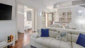 Una sala de estar moderna con un sofá, un televisor de pantalla plana y una zona de comedor con una mesa y sillas.