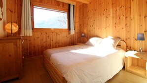 Una habitación de madera con una cama, una mesita de noche, una lámpara y una ventana.
