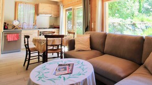 Interior acogedor de una cabaña con comedor, cocina y sofá junto a una ventana.
