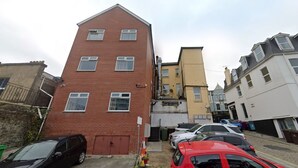 A narrow street with multi-story buildings, parked cars, and a visible shop entrance. - Luxury Oceana Apartment, Central City Centre, Newly Refurbished (Plymouth)
