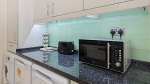 A kitchen with a microwave, toaster, and washing machine. - Luxury Oceana Apartment, Central City Centre, Newly Refurbished (Plymouth)