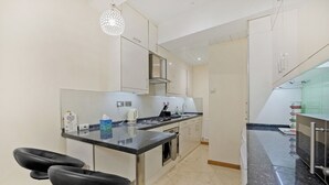 A modern kitchen with a central island, stainless steel appliances, and a hanging light fixture. - Luxury Oceana Apartment, Central City Centre, Newly Refurbished (Plymouth)