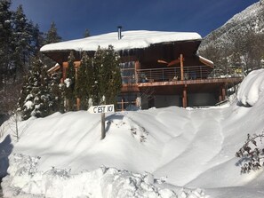 Una cabaña nevada con un cartel que dice 'C'EST ICI' al frente.