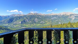 Blick auf Berge vom Balkon mit Holzwertung und Grünpflanzen.