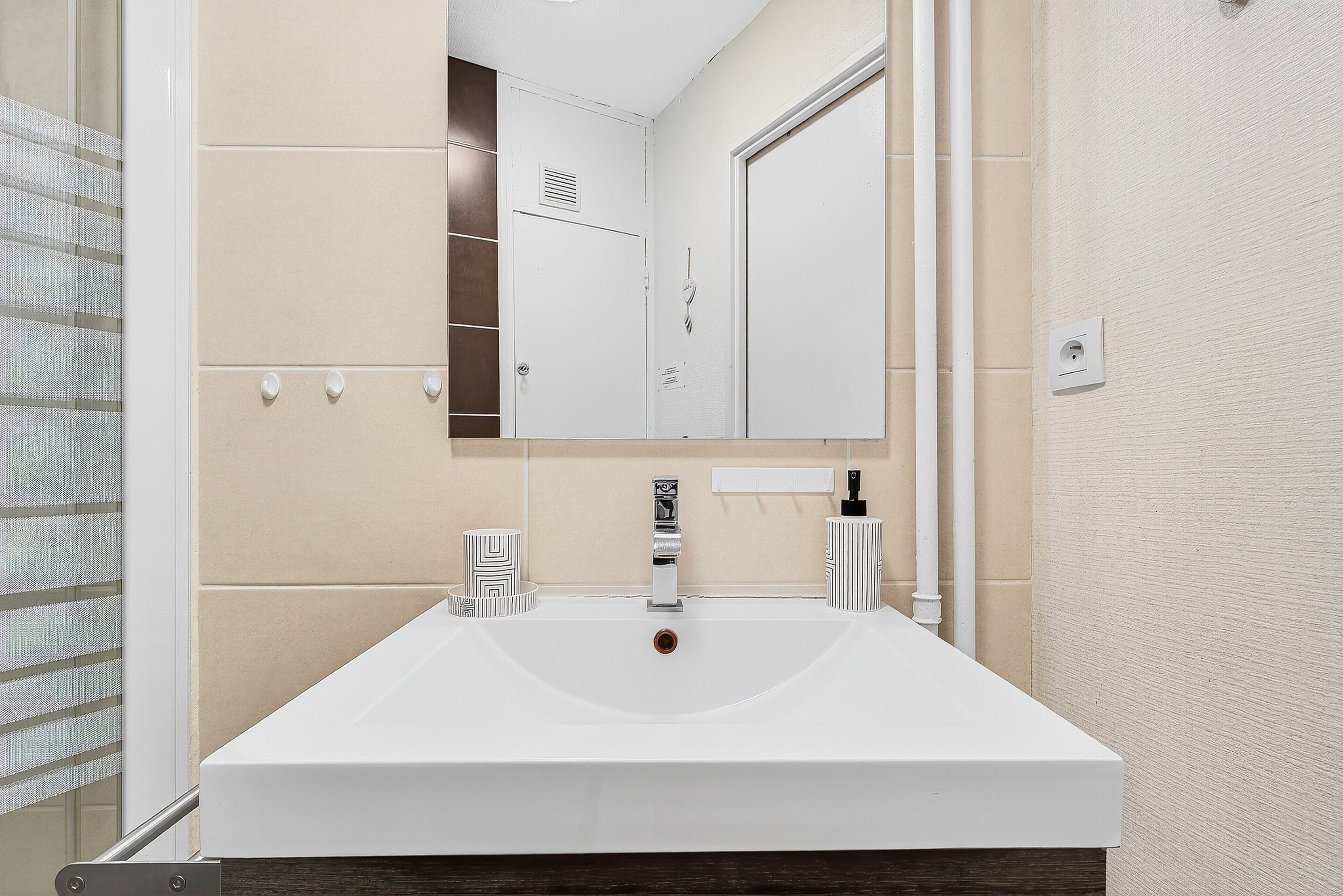 Een badkamer met een witte wastafel, een spiegel en een handdoekhouder.