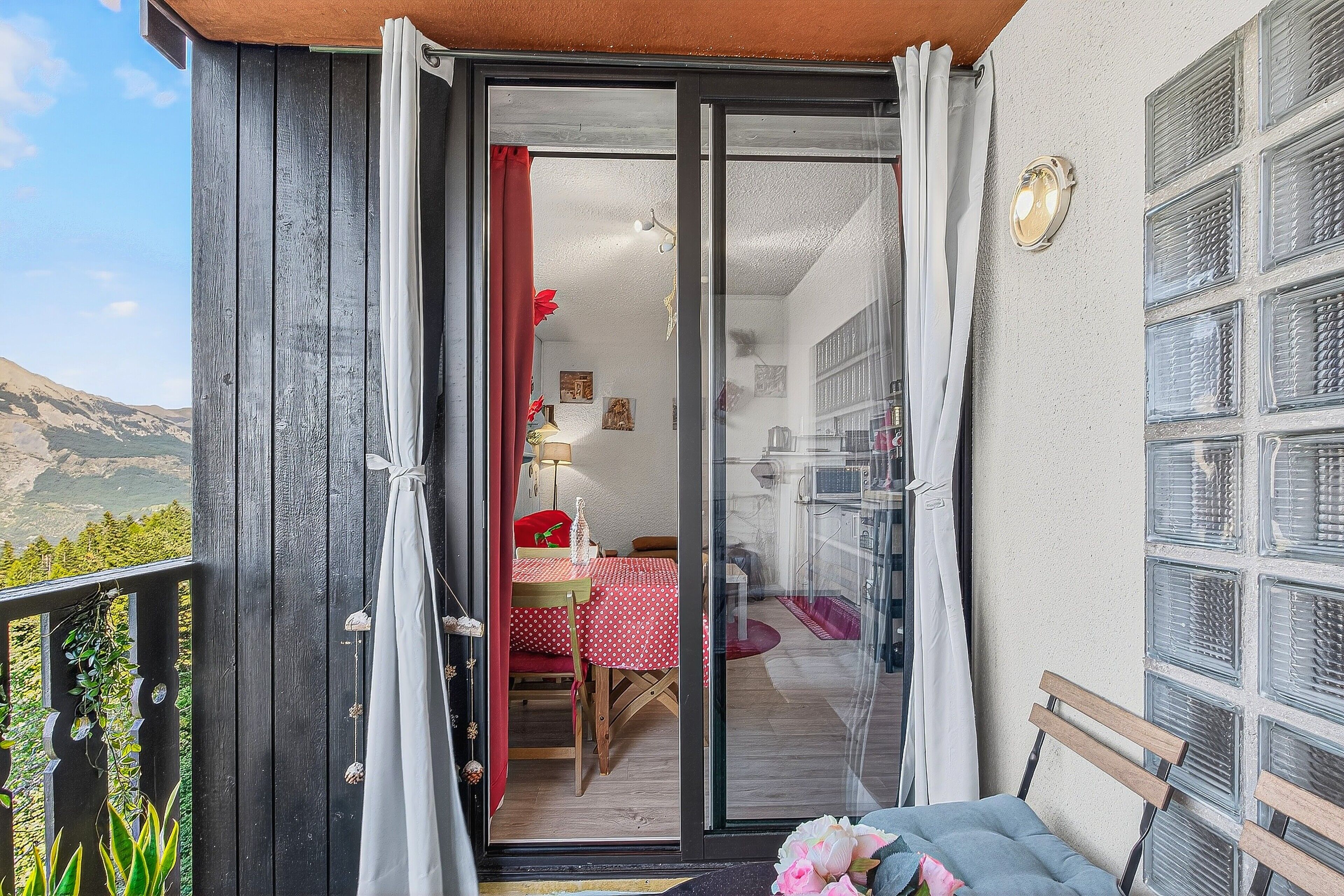 Ein Balkon mit Holzgeländer, einem Tisch mit rotem Tischläufer und einem Stuhl.