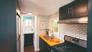 Enjoy cooking in this well-equipped kitchen with a stainless steel sink, gas stove, and black cabinets.