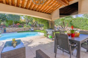 Una terrazza esterna con piscina, barbecue e zona pranzo con sedie e tavolo.