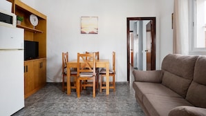 A compact living space with a kitchenette, a dining table with chairs, a sofa, a painting on the wall, and a door leading to another room. - Holiday Home 'Casa Francisco' with Private Pool, Private Terrace and Air Conditioning (Conil de la Frontera)