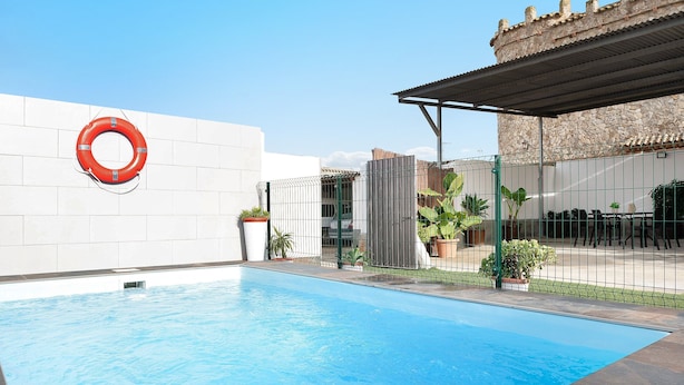 A swimming pool with a lifebuoy, a stone building, and potted plants. - Holiday Home 'Casa Francisco' with Private Pool, Private Terrace and Air Conditioning (Conil de la Frontera)
