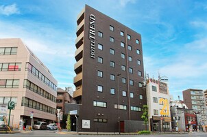 Un hotel moderno con un llamativo letrero que dice 'HOTEL TREND', varios pisos y un estacionamiento con un letrero de 'P'.
