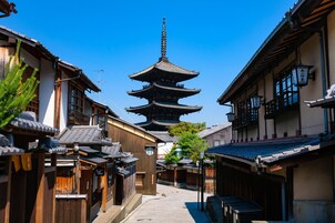 Una calle japonesa tradicional con edificios de madera, una pagoda y un cielo azul despejado.