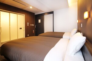 Habitación de hotel con dos camas, un armario y una puerta con cerradura.