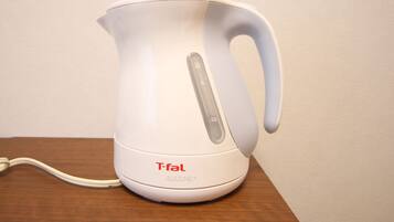 A white electric kettle with a handle and control panel, placed on a wooden surface.