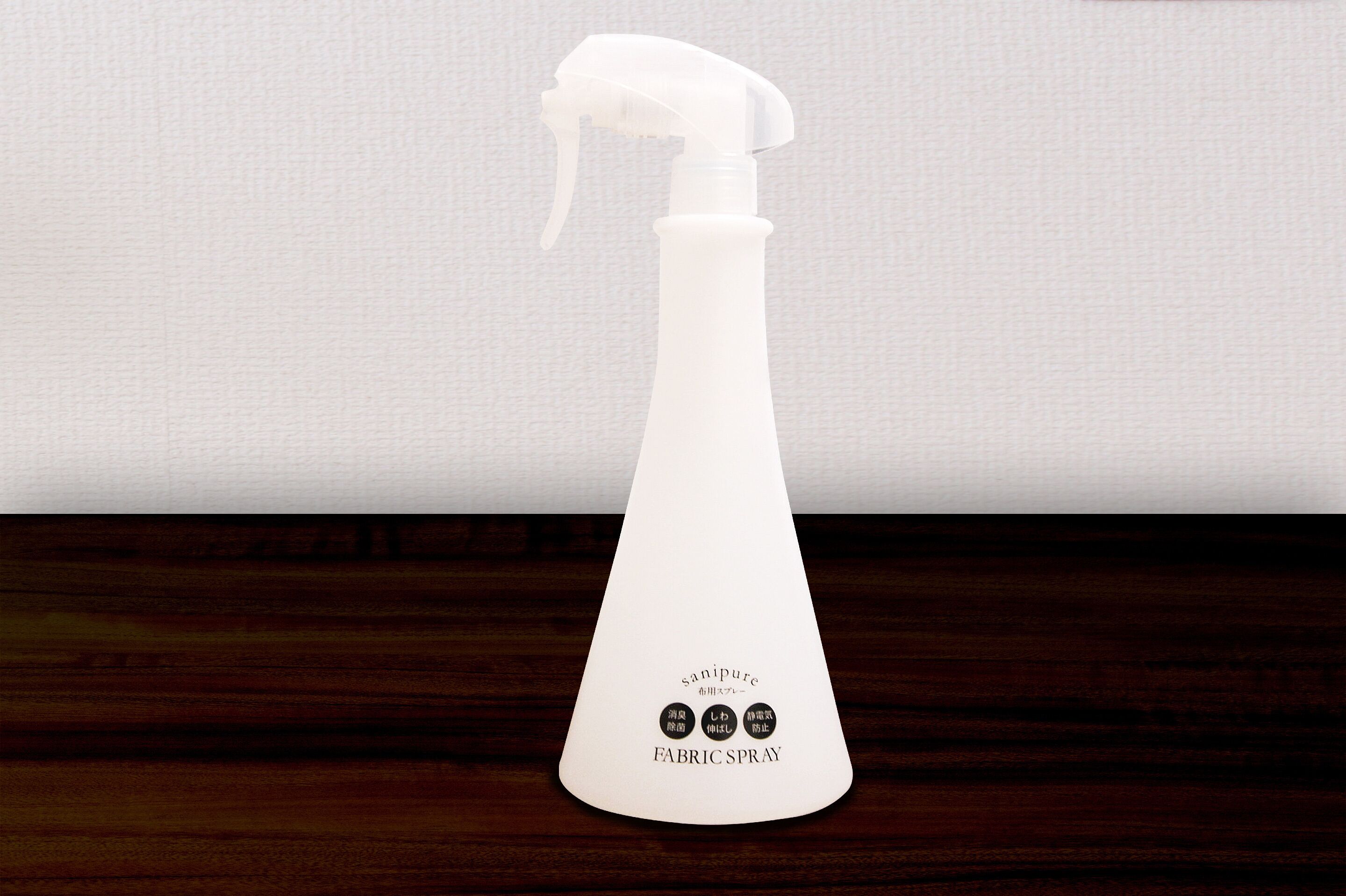 Un pulverizador de tela blanco con la etiqueta "sanipure" y "SPRAY PARA TELA" sobre una superficie de madera.