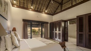 A spacious bedroom with a large bed, a ceiling fan, and a view through a sliding door to an outdoor area. - Villa Gading by Alfred in Bali (Seminyak)