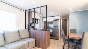 A modern kitchen with a refrigerator, stove, and cabinets. There is a dining area with a table and chairs.