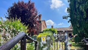 A garden with a wooden gate, a stone building, and a clear sky. - Holiday Home 'Il Forcone' with Shared Pool, Wi-Fi and Air Conditioning (Panicale)