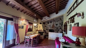 A rustic kitchen with stone walls, wooden beams, and various kitchen utensils hanging on the wall. - Holiday Home 'Il Forcone' with Shared Pool, Wi-Fi and Air Conditioning (Panicale)
