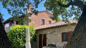 A stone house with a tiled roof, a covered porch, and a well-maintained garden. - Holiday Home 'Il Forcone' with Shared Pool, Wi-Fi and Air Conditioning (Panicale)