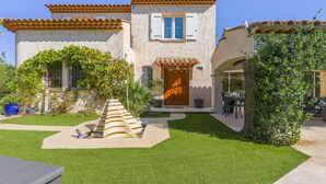 Una casa con techo de tejas, una puerta principal y un pequeño jardín con un sendero que lleva a la puerta.