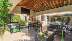Un patio al aire libre con una parrilla, una mesa de comedor y un sofá.