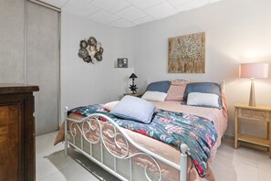 Un dormitorio con estructura de cama metálica, mesita de noche de madera, lámpara de noche y pared decorada.