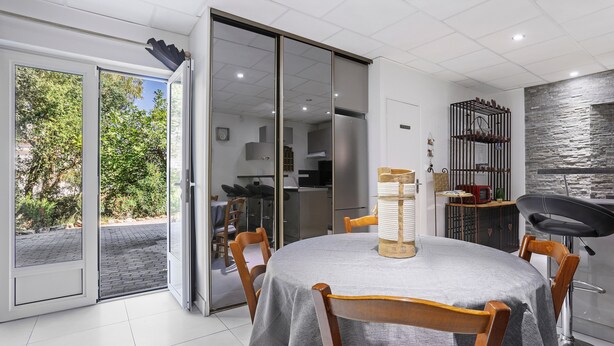 A dining area with a table, chairs, and a view through a sliding glass door.