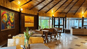 Un restaurante con paredes de madera, una chimenea de ladrillo y un ventanal con vistas a la vegetación.
