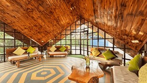 Una habitación amplia con vigas de madera, ventanas grandes y un suelo con estampado geométrico.