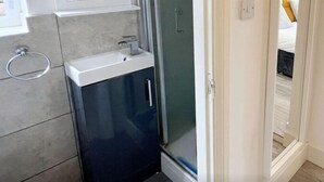 A modern bathroom with a glass shower enclosure, a built-in sink, and a mirror above the sink. - Minet Gardens Central-Suite 3 (London)