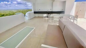 A modern balcony with a dining area, a sofa, and a view of the landscape. - PH Cana Rock 2B Punta Cana (Punta Cana)