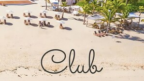 A beach resort with thatched-roof structures, palm trees, and sun loungers. - PH Cana Rock 2B Punta Cana (Punta Cana)