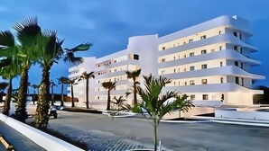 A modern multi-story hotel with a flat facade, balconies, and a clear sky. - PH Cana Rock 2B Punta Cana (Punta Cana)