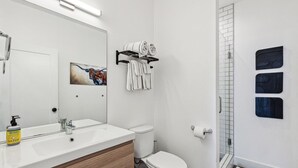 Une salle de bain moderne avec un lavabo blanc, des toilettes et un espace douche.
