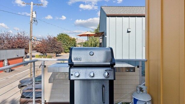 A Weber Spirit gas grill on an outdoor balcony with a view of a building and a parked car. - * * * * *Modern Missoula Bungalow* * * * * (Missoula)