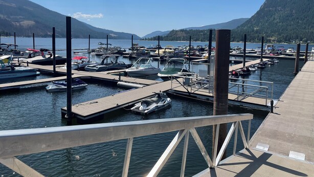 A marina with boats docked, a wooden pier, and a mountainous backdrop.
