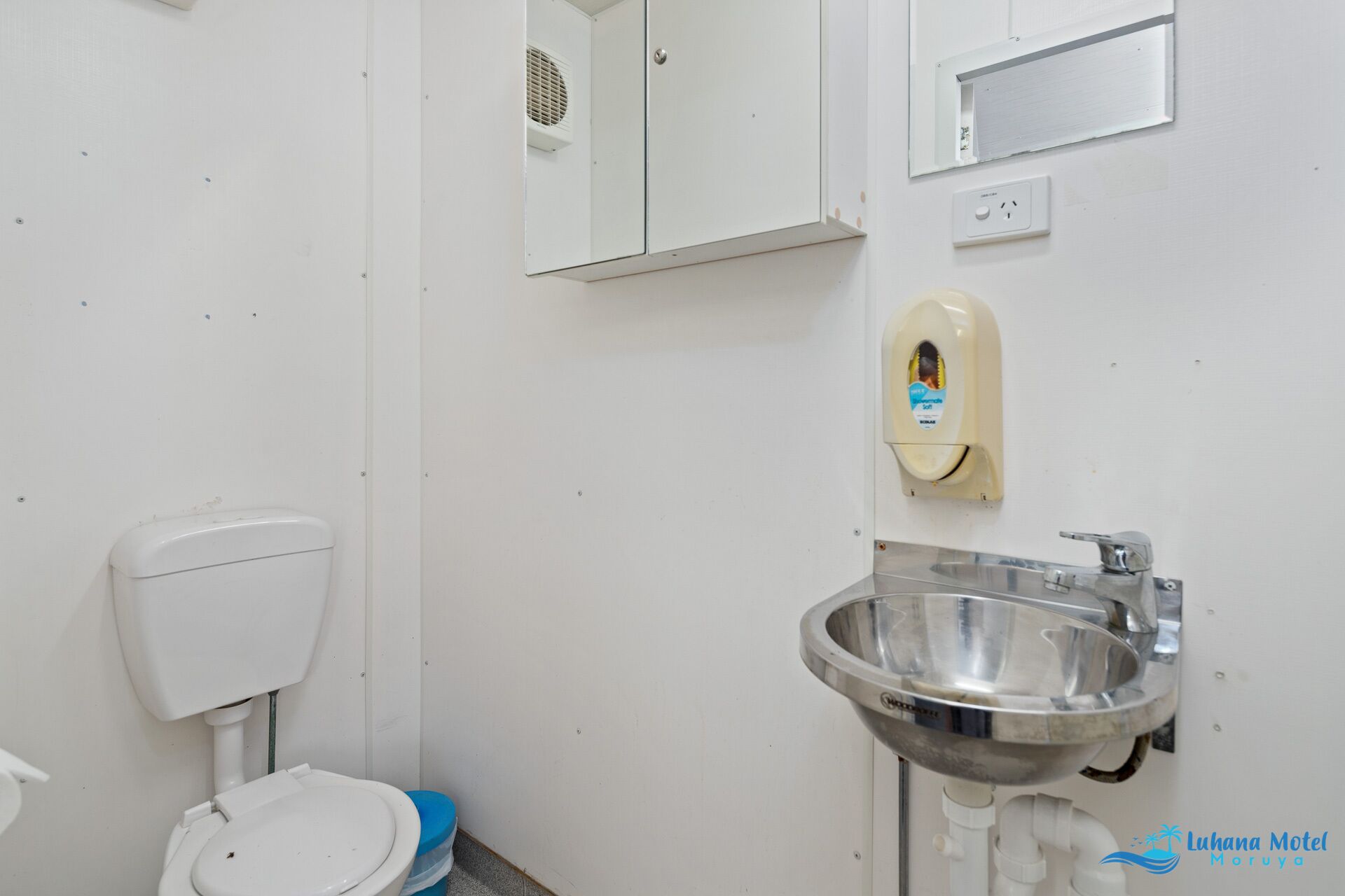 Un baño con inodoro, secamanos, lavamanos y espejo.