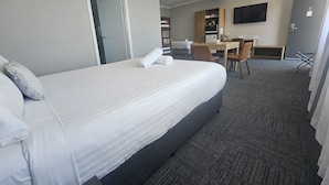 Una habitación de hotel con una cama grande, un escritorio, una silla, un televisor y un ventilador de techo.