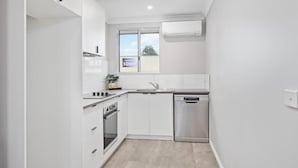 Una cocina moderna con armarios blancos, un lavavajillas de acero inoxidable y un ventanal con vistas.