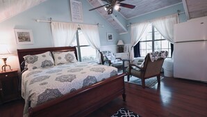 A bedroom with a wooden bed, a chair, a desk, and a refrigerator. - Romantic guest house within walking distance from Lake Texoma. (Pottsboro)