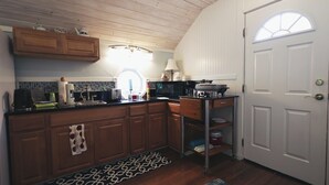 A kitchen with wooden cabinets, a black countertop, a stove, and a white door. - Romantic guest house within walking distance from Lake Texoma. (Pottsboro)