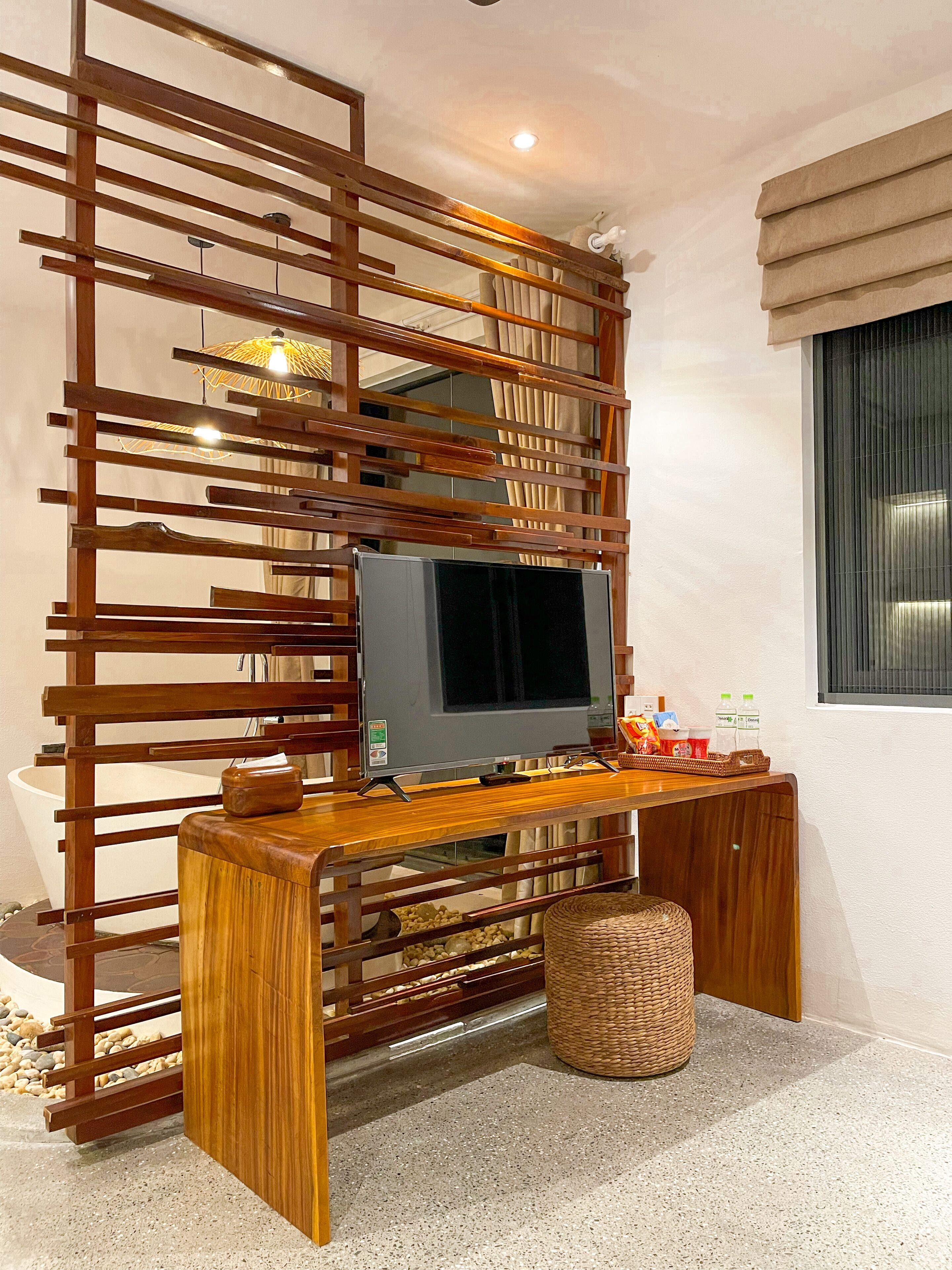Ein TV-Schrank aus Holz mit einem Flachbildfernseher, einem gewebten Korb und einem kleinen Tisch mit Flaschen und einer Fernbedienung.